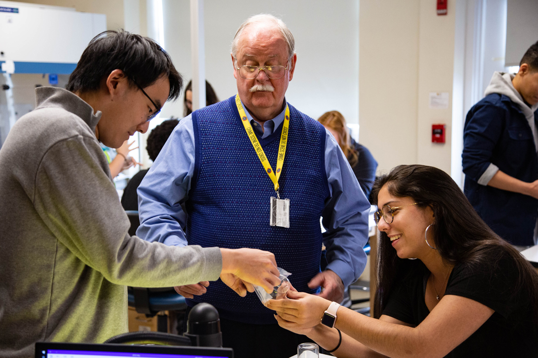 Department Chair Walter Rowe supervises two students doing lab work.